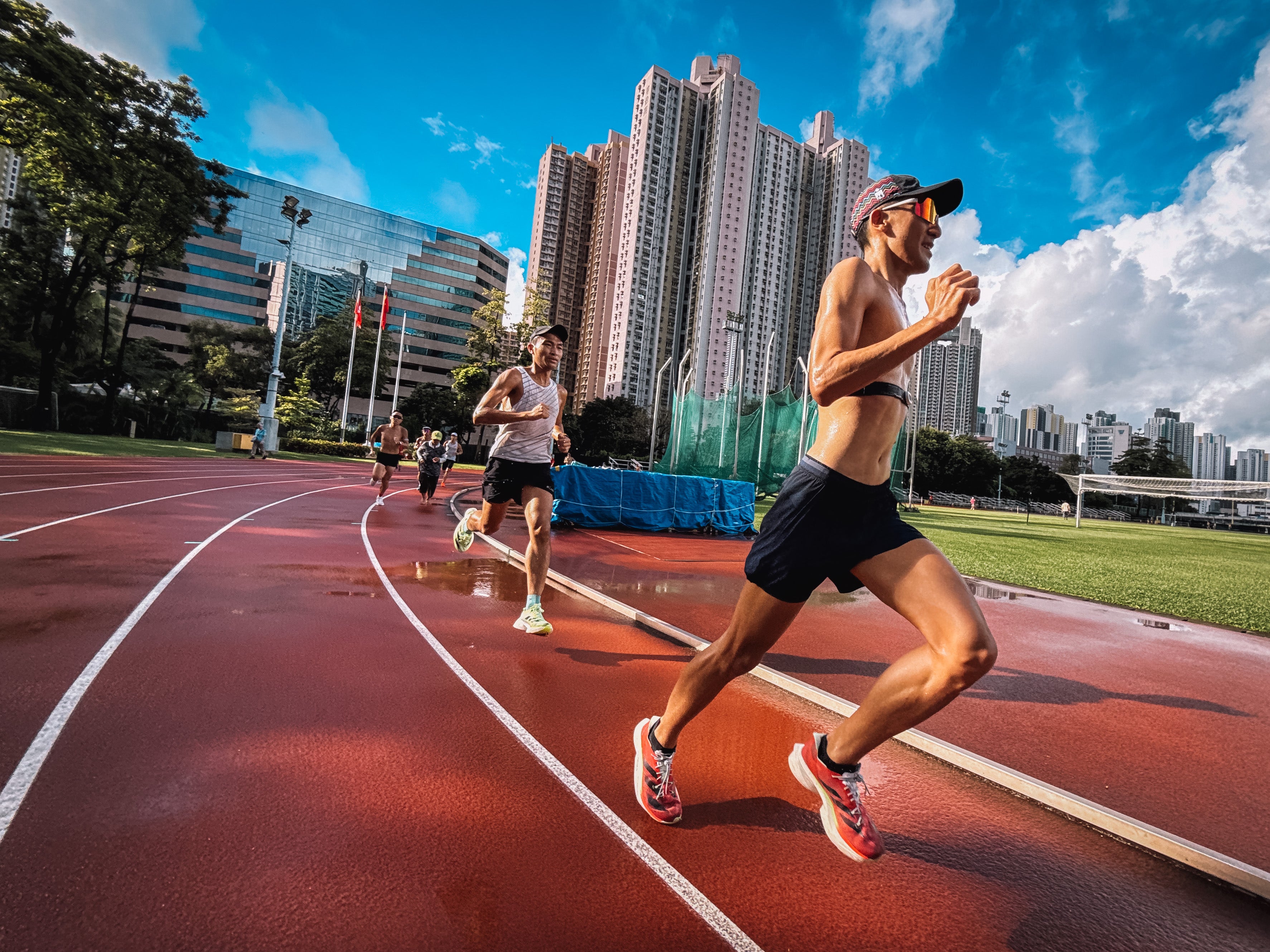 Runners on a track with urban skyline in the background